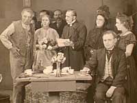 Fra mørke til lys 1928. Scenen, hvor de onde, rige spekulanter kræver huslejeforhøjelse af den fattige familie