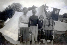 4 unge piger foran deres telt, der er pyntet med trepile-fane, på DSU sommerlejr